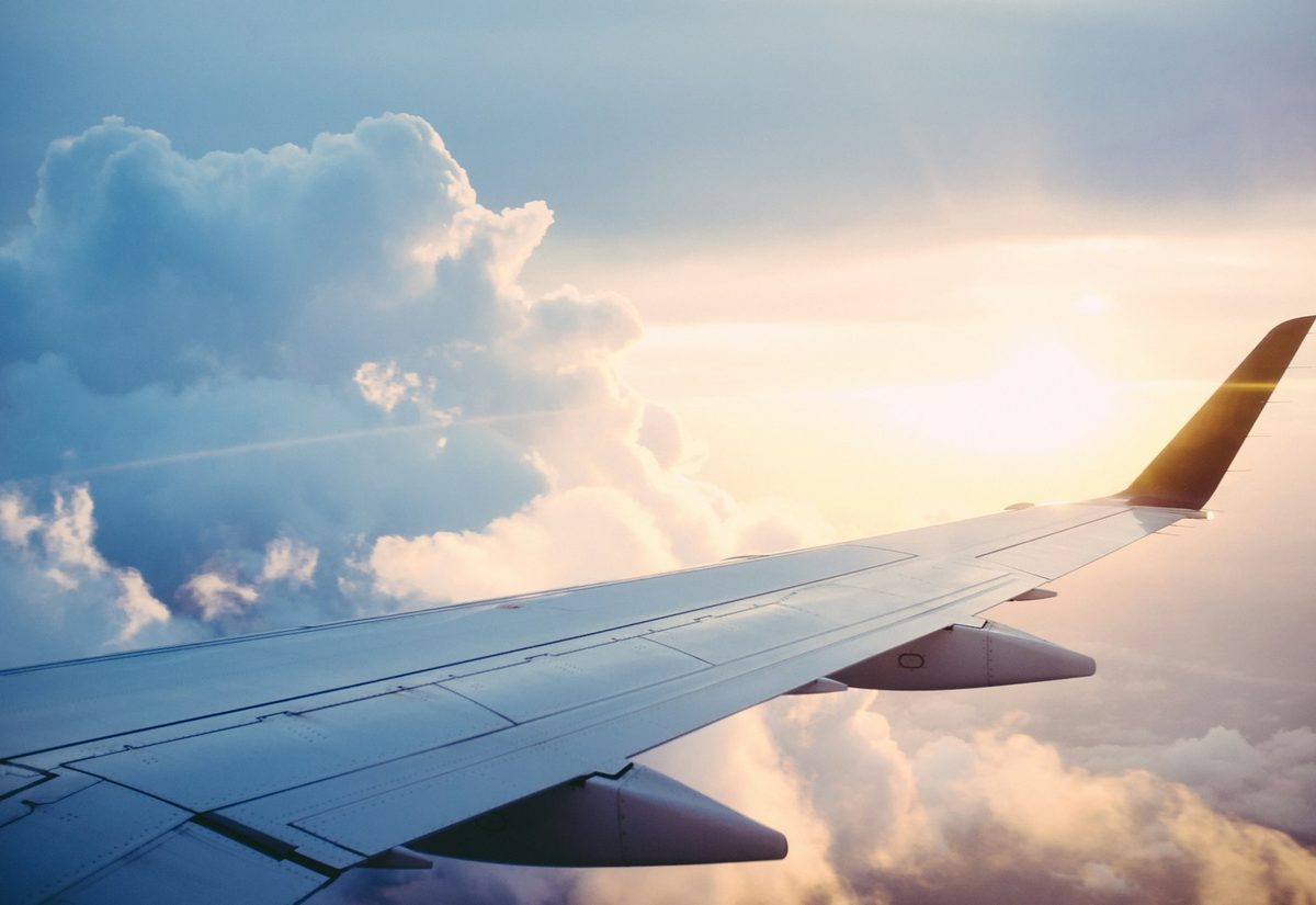 Airplane wing above the clouds at sunset
